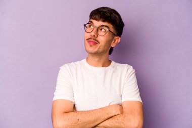 Mor arka planda izole edilmiş genç beyaz adam hedeflere ve amaçlara ulaşmayı hayal ediyor.