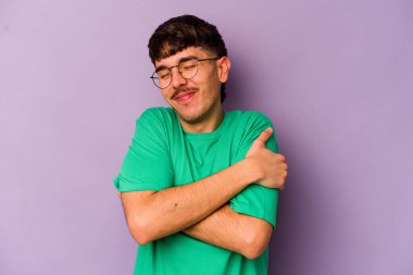 Mor arka planda izole edilmiş genç beyaz adam. Kucaklaşma, kaygısız gülümseme ve mutluluk..