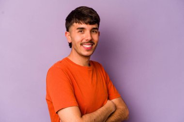 Mor arka planda izole olmuş genç beyaz adam kendini güvende hissediyor, kararlılıkla kollarını kavuşturuyor..