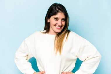 Mavi arka planda izole edilmiş genç beyaz kadın mutlu, güler yüzlü ve neşeli..