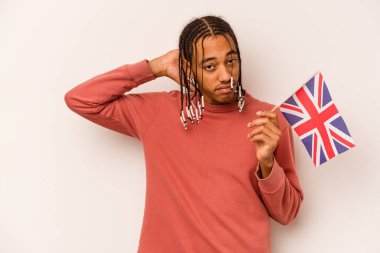 Beyaz arka planda izole edilmiş bir İngiliz bayrağı tutan genç Afrikalı Amerikalı adam kafasının arkasına dokunuyor, düşünüyor ve bir seçim yapıyor..