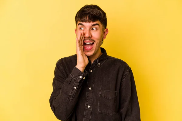 Young caucasian man isolated on yellow background shouting excited to front.
