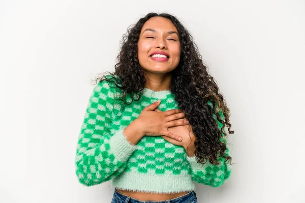 Beyaz arka planda izole edilmiş genç İspanyol kadın gülüyor, ellerini kalbe koyuyor, mutluluk kavramını koruyor..