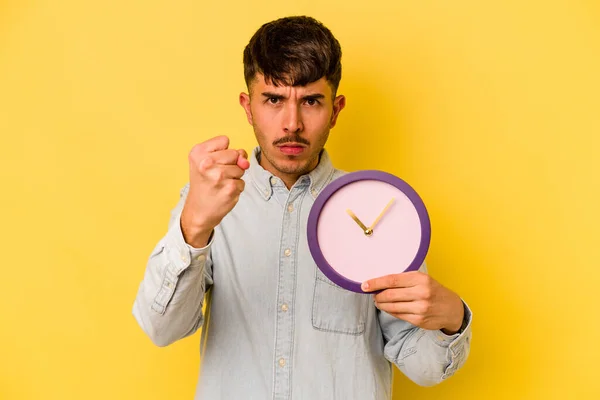 Jovem Hispânico Segurando Relógio Isolado Fundo Amarelo Mostrando Punho Para — Fotografia de Stock