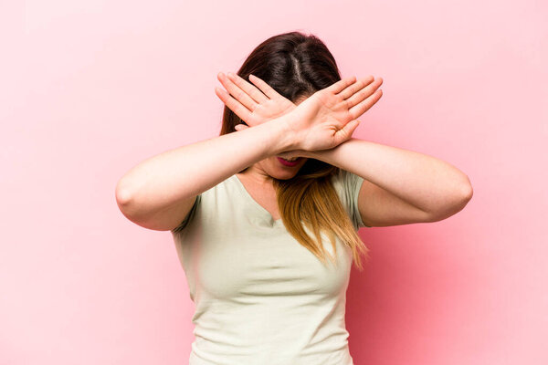 Young caucasian woman isolated on pink background keeping two arms crossed, denial concept.