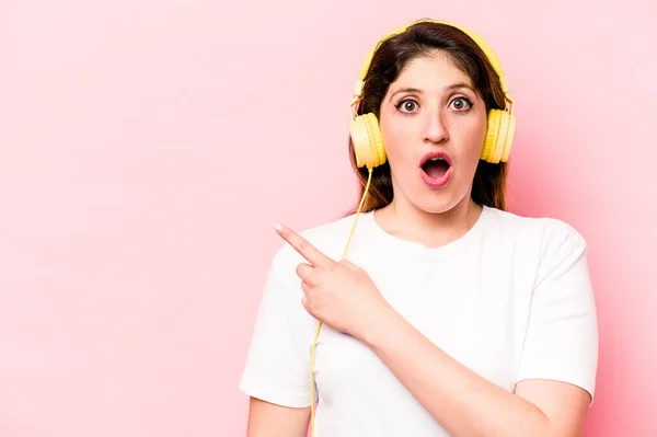 Young Caucasian Woman Listening Music Isolated Pink Background Pointing Side — Φωτογραφία Αρχείου