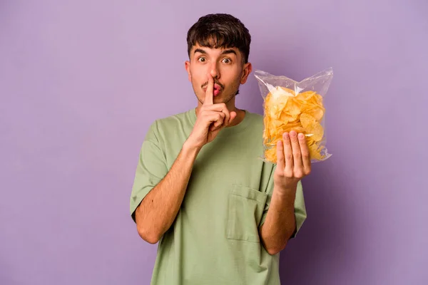 Jonge Latijns Amerikaanse Man Met Chips Geïsoleerd Paarse Achtergrond Houden — Stockfoto