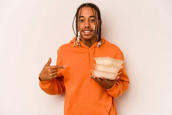 Young African American man holding tupperware isolated on white background person pointing by hand to a shirt copy space, proud and confident