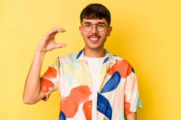 Jovem Caucasiano Isolado Fundo Amarelo Segurando Algo Pouco Com Dedos — Fotografia de Stock