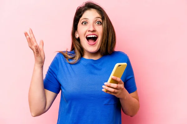 분홍색 배경에서 고립된 전화를 인디오 여성은 놀랍고 흥분되어 소식을 듣는다 — 스톡 사진