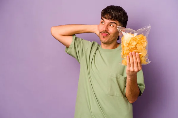 Jonge Latijns Amerikaanse Man Met Chips Geïsoleerd Paarse Achtergrond Raken — Stockfoto