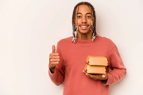 Młody Afroamerykanin Trzyma Hamburgera Białym Tle Uśmiechając Się Podnosząc Kciuk — Zdjęcie stockowe