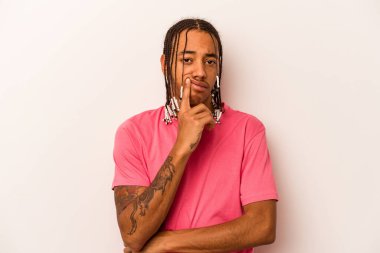 Beyaz arka planda izole edilmiş genç Afrikalı Amerikalı adam alaycı bir ifadeyle kameraya bakıyor..