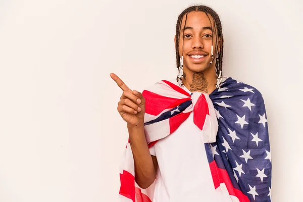 白地にアメリカ国旗を掲げた若いアフリカ系アメリカ人男性が笑顔で脇を指差して 空白の空間で何かを見せる — ストック写真