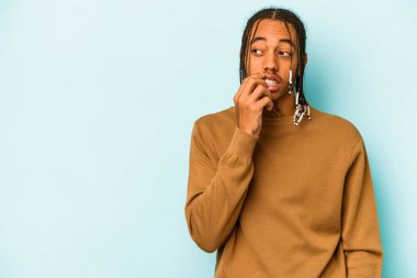 Genç Afrikalı Amerikalı bir adam mavi arka planda izole edilmiş rahat bir şekilde bir şeyin fotokopi odasına baktığını düşünüyor..