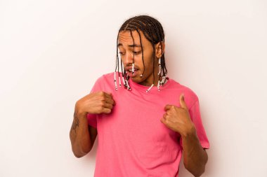 Beyaz arka planda izole edilmiş genç bir Afro-Amerikan erkeği parmağını gösterip gülümseyerek şaşırdı..