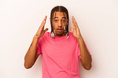 Genç Afrikalı Amerikalı bir adam beyaz arka planda izole edilmiş zaferi ya da başarıyı kutluyor, şaşırmış ve şok olmuş..