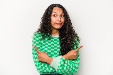 Beyaz arka planda izole edilmiş genç İspanyol kadın iki seçenek arasında seçim yapmaya çalışıyor..