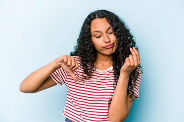 Mavi arka planda izole edilmiş genç İspanyol kadın parasız olduğunu gösteriyor..