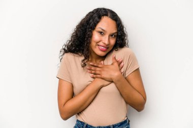 Beyaz arka planda izole edilmiş genç İspanyol kadın, avuçlarını göğsüne bastıran dostça bir ifadeye sahiptir. Aşk konsepti.