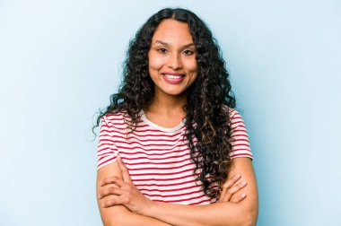 Mavi arka planda kendini güvende hisseden, kararlılıkla kollarını kavuşturan genç İspanyol kadın..