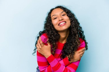 Mavi arka planda yalnız yaşayan genç İspanyol kadın gülüyor ve eğleniyor..