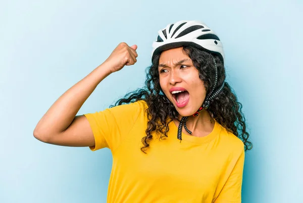 勝利の後に拳を上げ青い背景に隔離されたヘルメット自転車を身に着けている若いヒスパニック女性 勝者の概念 — ストック写真