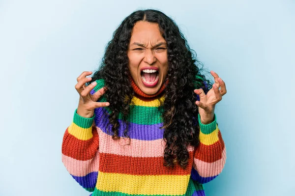 Mavi arka planda izole edilmiş genç İspanyol kadın öfkeyle bağırıyor..