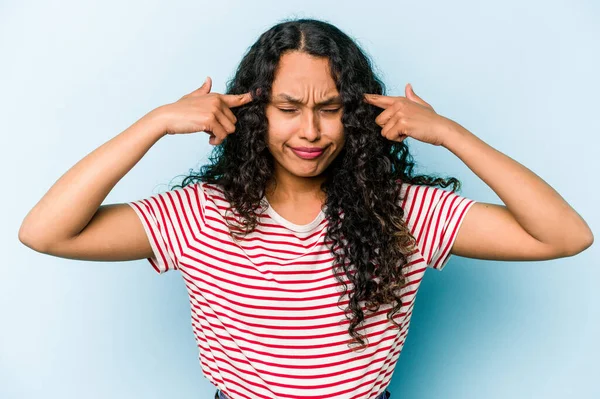 Mavi arka planda izole edilmiş genç İspanyol kadın bir işe odaklanmış, işaret parmaklarını işaret ediyor..