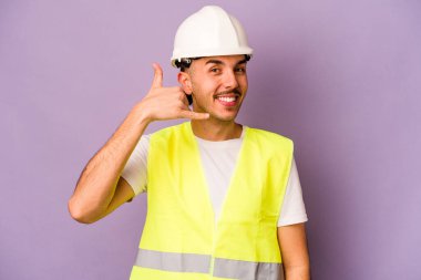 Mor arka planda izole edilmiş genç İspanyol işçi parmaklarıyla bir cep telefonu hareketi gösteriyor..