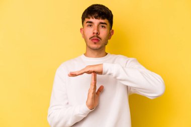 Sarı arka planda izole edilmiş genç beyaz adam bir mola hareketi gösteriyor..