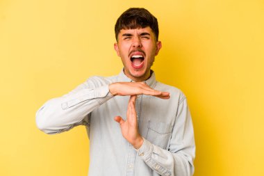 Sarı arka planda izole edilmiş genç beyaz adam bir mola hareketi gösteriyor..