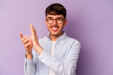 Mor arka planda izole olmuş genç beyaz adam enerjik ve rahat hissediyor, ellerini ovuşturuyor..