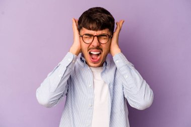 Kafkasyalı genç adam mor arka planda izole edilmiş kulakları kulaklarıyla kapatıyor çok fazla ses duymamaya çalışıyor..
