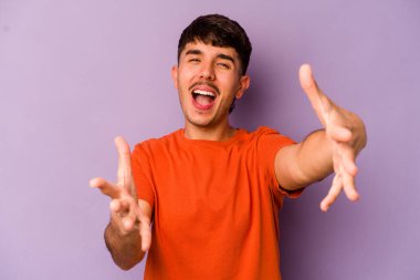 Mor arka planda izole genç beyaz adam kameraya sarıldığı için kendinden emin hissediyor..