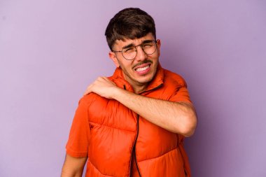 Mor arka planda izole edilmiş, omuz ağrısı olan genç beyaz bir adam..