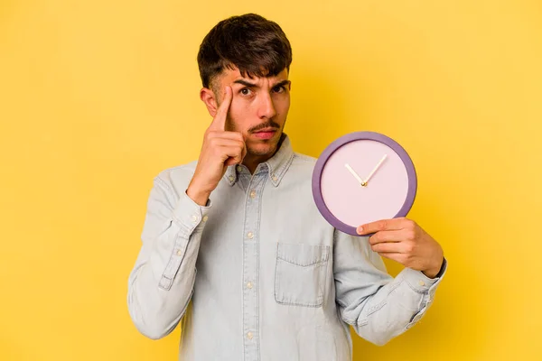 Jeune Homme Hispanique Tenant Une Horloge Isolée Sur Fond Jaune — Photo