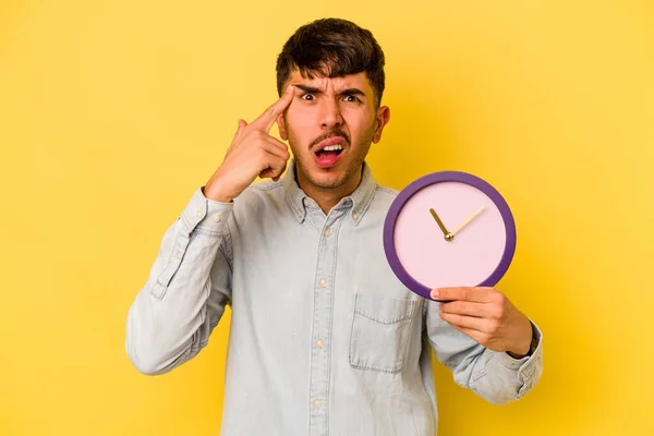 Молодий Іспаномовний Чоловік Тримає Годинник Ізольований Жовтому Тлі Показуючи Жест — стокове фото