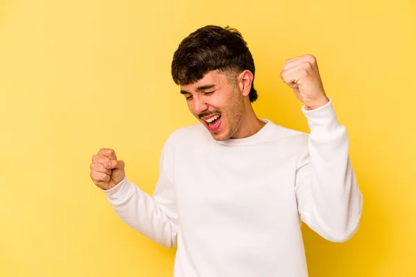 Young caucasian man isolated on yellow background dancing and having fun.
