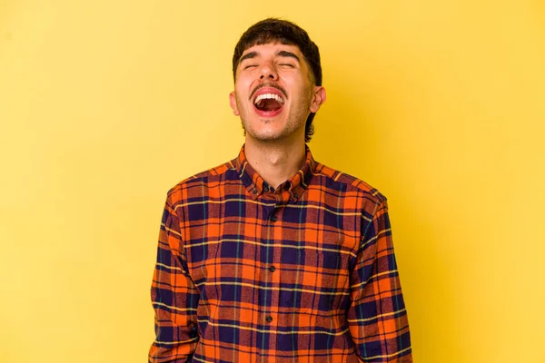 Young caucasian man isolated on yellow background relaxed and happy laughing, neck stretched showing teeth.