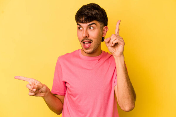 Молодой кавказский человек выделяется на желтом фоне, указывая на разные копировальные пространства, выбирая одно из них, показывая пальцем.