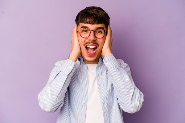 Young caucasian man isolated on purple background screaming, very excited, passionate, satisfied with something.