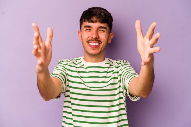 Mor arka planda izole olmuş genç beyaz bir adam zaferi ya da başarıyı kutluyor, şaşırıyor ve şok oluyor..