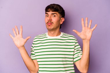 Mor arka planda izole genç beyaz adam yakın bir tehlike nedeniyle şoka uğruyor