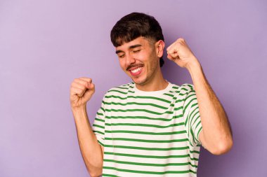 Mor arka planda izole genç beyaz adam özel bir günü kutluyor, atlıyor ve enerjiyle kollarını kaldırıyor..