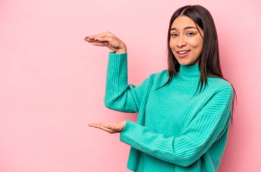 Pembe arka planda izole edilmiş genç İspanyol kadın elleri arasında bir kopya alanı tutarken şok ve hayrete düştü..