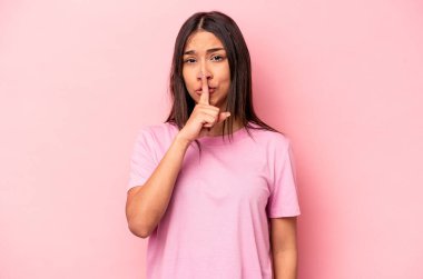Pembe arka planda izole edilmiş genç İspanyol kadın ya sır saklıyor ya da sessizlik istiyor..