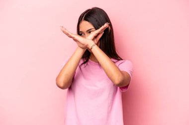 Pembe arka planda izole edilmiş genç İspanyol kadın iki kolu çapraz tutuyor, inkar kavramı.