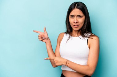 Mavi arka planda izole edilmiş genç İspanyol kadın işaret parmağıyla bir fotokopi alanını işaret ederek şok oldu..