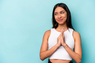 Latin kökenli genç bir kadın mavi arka planda izole edilmiş. Aklında bir plan kuruyor..